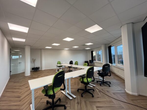 Moderne vergaderruimte aan de Lange Dreef met flexibele bureaus en groene bureaustoelen.